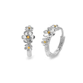 A pair of sterling silver hoop earrings, each adorned with three small daisies with gold-plated centres, shown from the front and side on a white background.